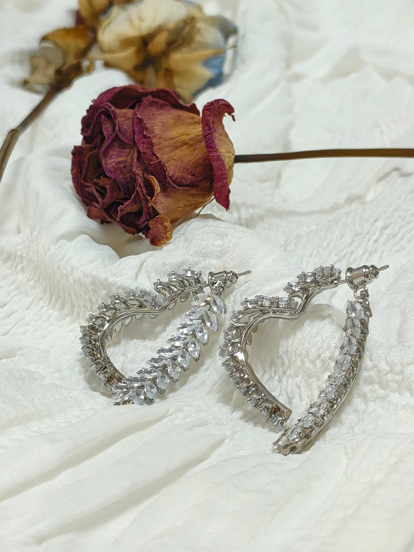 Close-up of Wheat Cross Heart Earrings highlighting intersecting wheat motifs