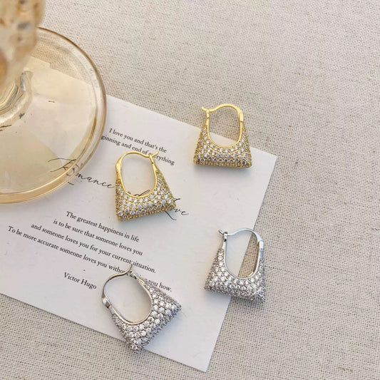 Close-up of handbag motif earrings with sparkling gemstone details